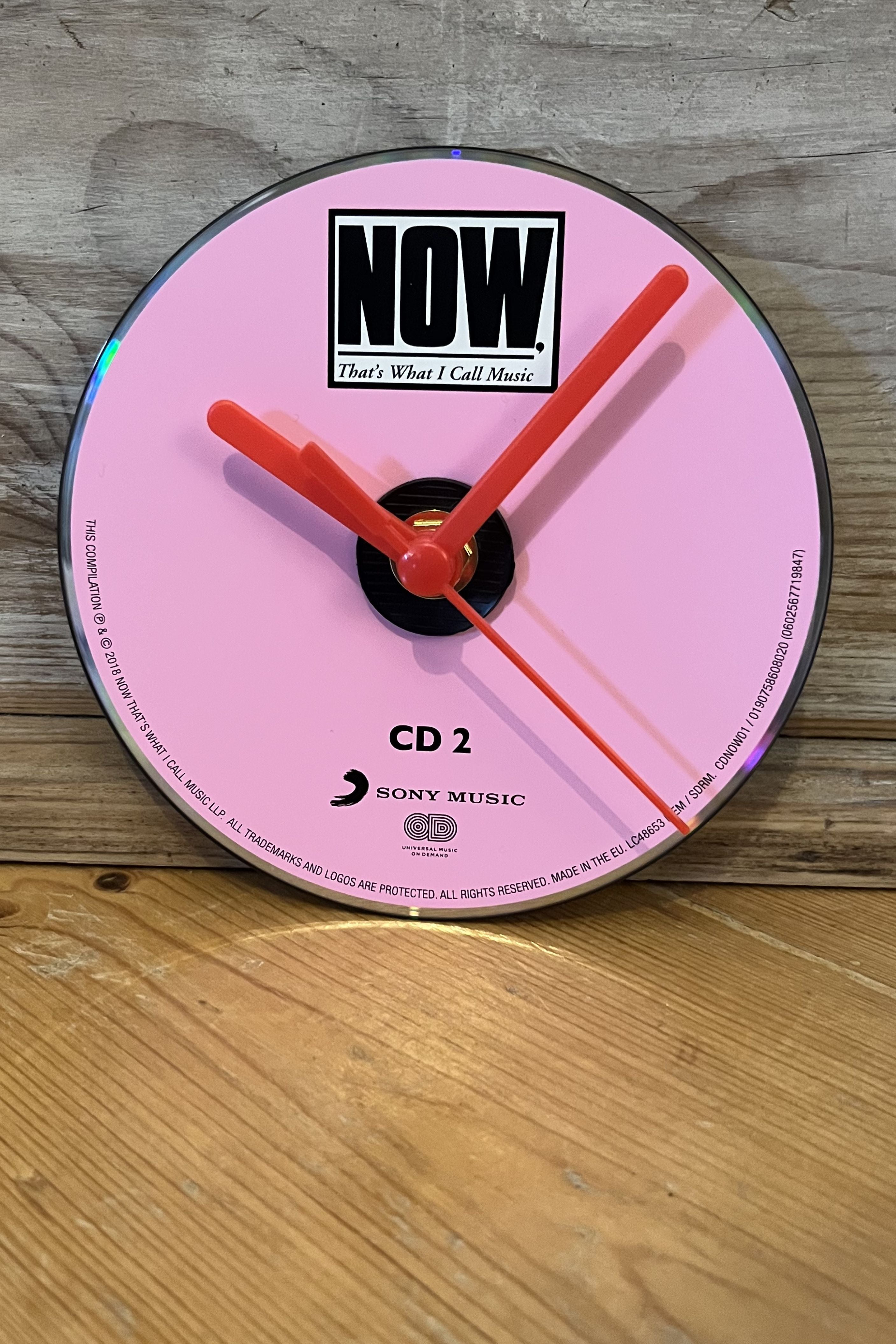 Close‑up of Now That’s What I Call Music CD clock showing vibrant cover design